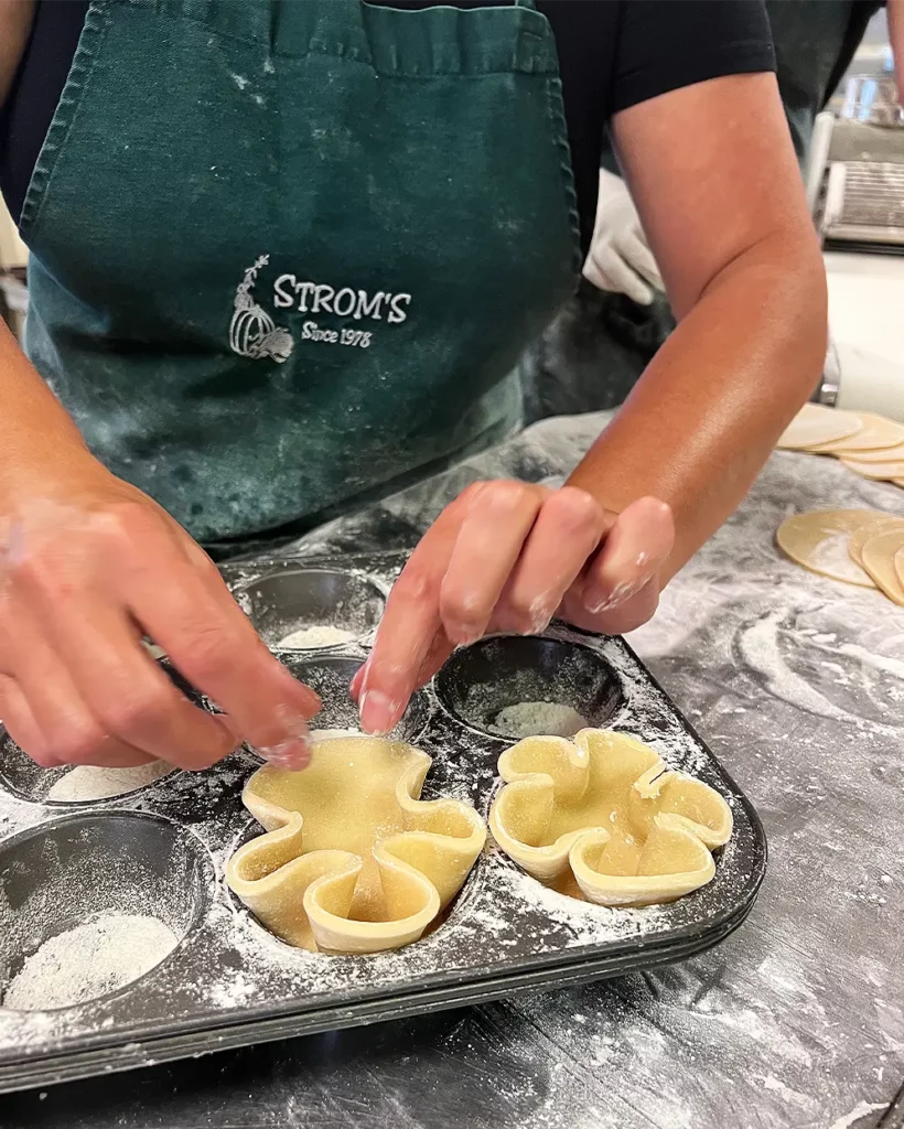 A baker at Strom's Farm & Bakery in Guelph hand-forming the signature flower-shaped pastry shells from scratch for our homemade Ontario butter tarts.